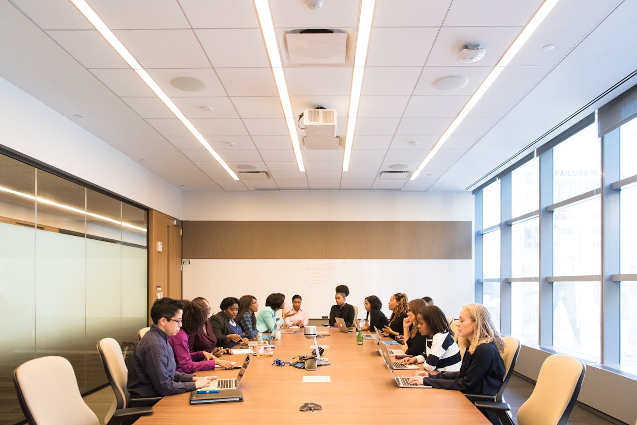 A professional meeting in a conference room with a group of people seated at a table, discussing ideas.