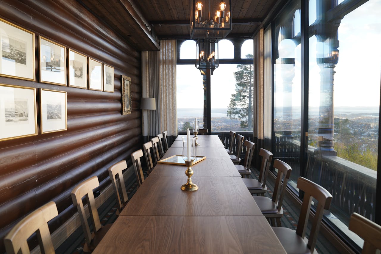 A beautifully arranged conference room featuring a long table, chairs, and elegant candlesticks, set in a bright space with large windows.